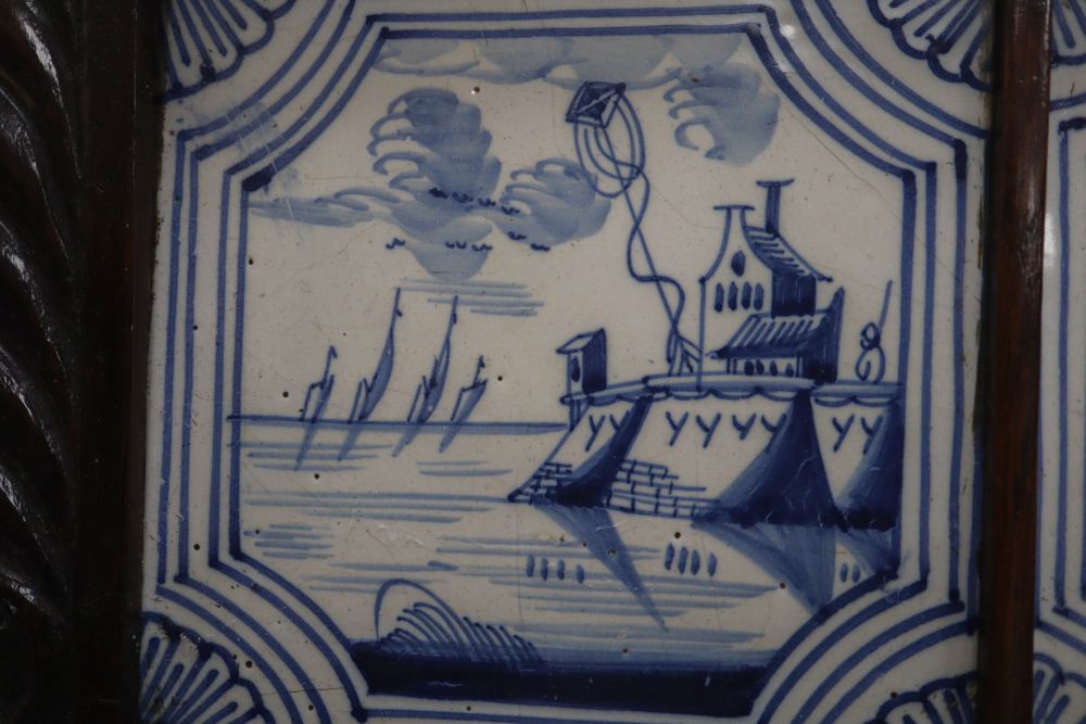 Four blue and white Delft tiles, housed in a carved oak frame, overall 35cm sq.